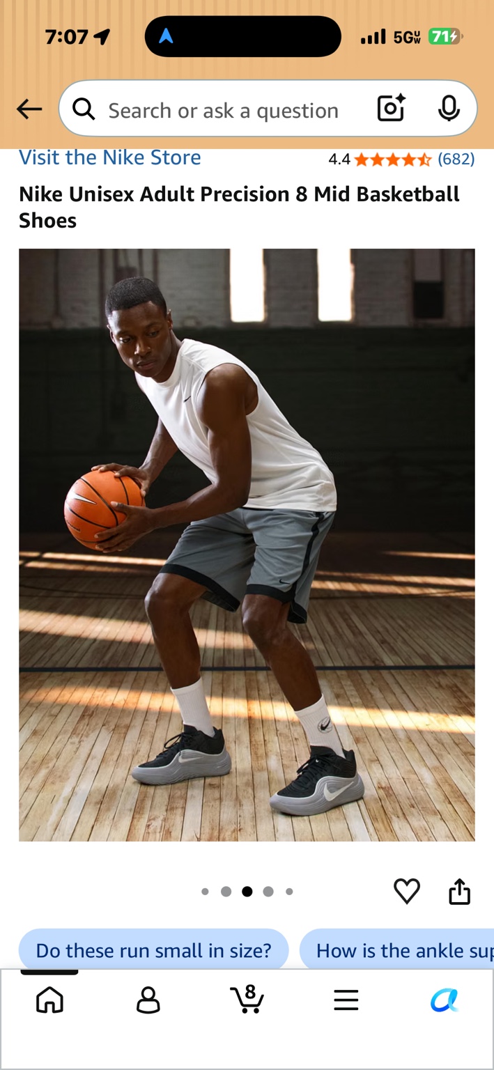 Basketball player wearing gray and black Nike Precision 8 Mid basketball shoes on an indoor court